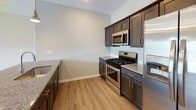 Located at 4224 California Rd in Orchard Park, NY, this single-floor residence offers a thoughtfully designed open-concept layout that connects the living, dining, and kitchen areas seamlessly. The kitchen is a standout feature, equipped with dark espresso cabinetry, granite countertops, a subway tile backsplash, and a full suite of stainless steel appliances including a gas range, over-the-range microwave, and French door refrigerator. A central island with matching granite provides additional prep and seating space, while pendant lighting and recessed fixtures add a polished finish.

The living area extends naturally from the kitchen and features light hardwood-style flooring, neutral wall tones, and a sliding glass door that opens to an outdoor balcony, allowing ample natural light and outdoor views. The bedrooms are carpeted and well-proportioned, each featuring large windows that bring in natural light and views of the surrounding neighborhood. The bathroom includes a shower-tub combination, wood-look vinyl flooring, and clean, neutral finishes throughout. Overall, the home presents a bright, modern aesthetic with consistent, quality finishes across every room.