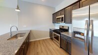 Located at 4224 California Rd in Orchard Park, NY, this single-floor residence offers a thoughtfully designed open-concept layout that connects the living, dining, and kitchen areas seamlessly. The kitchen is a standout feature, equipped with dark espresso cabinetry, granite countertops, a subway tile backsplash, and a full suite of stainless steel appliances including a gas range, over-the-range microwave, and French door refrigerator. A central island with matching granite provides additional prep and seating space, while pendant lighting and recessed fixtures add a polished finish.

The living area extends naturally from the kitchen and features light hardwood-style flooring, neutral wall tones, and a sliding glass door that opens to an outdoor balcony, allowing ample natural light and outdoor views. The bedrooms are carpeted and well-proportioned, each featuring large windows that bring in natural light and views of the surrounding neighborhood. The bathroom includes a shower-tub combination, wood-look vinyl flooring, and clean, neutral finishes throughout. Overall, the home presents a bright, modern aesthetic with consistent, quality finishes across every room.