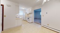 Located at 1392 Nash Rd in North Tonawanda, NY, this single-floor, 2-bedroom, 1-bathroom home offers a straightforward and functional layout with a clean, bright aesthetic throughout. The kitchen is designed in a classic galley style, featuring white cabinetry with ample upper and lower storage, light countertops, a stainless steel sink, and white appliances including an electric range, dishwasher, and refrigerator. Light tile flooring and a window with natural light enhance the kitchen's open feel, and it connects directly to the adjacent living area. The spacious primary bedroom is notably generous in size, finished with neutral carpet flooring, white walls, and two windows fitted with blinds that allow for natural light while maintaining privacy. A baseboard heating unit ensures year-round comfort. The second bedroom also features carpet flooring, white walls, and baseboard heating, providing a cozy and versatile space. The bathroom is well-appointed with a full tub and shower combination, a window for ventilation, a white vanity with storage, and clean tile flooring. Throughout the home, warm-toned wood doors with brass hardware add a consistent design detail. The overall ambiance is clean, neutral, and move-in ready.