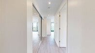 Located on an upper floor at 25 Gibbs Road in Toronto's Etobicoke neighbourhood, this 2-bedroom, 1-bathroom unit offers a modern, open-concept layout with clean lines and contemporary finishes. Light wood-tone laminate flooring runs throughout, complementing the bright white walls and creating a cohesive, airy feel.

The kitchen is well-appointed with high-gloss white upper cabinetry, wood-toned lower cabinets, a white subway tile backsplash, quartz countertops, and a full suite of stainless steel appliances including a refrigerator, electric range, built-in microwave, and dishwasher. A kitchen island with a quartz top and navy metal legs doubles as a dining area, accented by warm pendant lighting above.

Both bedrooms feature floor-to-ceiling windows with bold black frames, allowing generous natural light and sweeping views of the Toronto skyline, surrounding greenery, and urban streetscapes below. The primary bedroom includes mirrored sliding closet doors, while the second bedroom offers a bright, versatile space.

The bathroom is finished with large-format neutral tiles, a soaker tub with a curved shower rod, a wall-mounted vanity with a white countertop, and recessed lighting, delivering a clean and functional design. The overall ambiance of the unit is modern, bright, and well-suited for urban living.