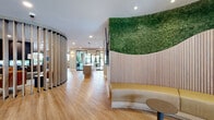 Located at 204 Wagaraw Road in Hawthorne, NJ, this thoughtfully designed single-floor amenity space combines contemporary architecture with warm, organic materials to create a refined and welcoming environment. The entry foyer features sleek black-framed glass doors, a stainless steel elevator, and light hardwood flooring that flows consistently throughout the space.

The main lounge area is anchored by a dramatic floor-to-ceiling fireplace clad in dark veined stone, offering seating on multiple sides. Curved slatted wood partitions elegantly define zones within the open layout, while a striking living moss wall installation adds a vibrant natural focal point above a built-in curved bench.

A private dining room showcases a live-edge wood communal table beneath amber glass pendant lights, framed by expansive black-framed windows with garden views and a wall of glass-front cabinetry with wine storage. Adjacent is a kitchenette with exposed brick walls, light wood cabinetry, white quartz countertops, and open shelving.

Private work nooks with built-in desks and carpeted floors offer quiet, focused workspaces. The fitness center is equipped with cardio machines, a power rack, and a punching bag, all illuminated by natural light. Sliding glass doors connect the lounge to an outdoor patio with additional seating.
