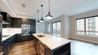 Located in Houston's sought-after 77027 corridor, this well-appointed one-bedroom, two-bathroom residence offers a thoughtfully designed single-level layout with upscale finishes throughout. Rich hardwood flooring flows seamlessly across the living spaces, complementing the neutral tones of the walls and crisp white trim.

The open kitchen is a standout feature, showcasing bold navy cabinetry with brushed gold hardware, pristine white quartz countertops, a herringbone tile backsplash, a gas cooktop, stainless steel wall oven, built-in microwave, and a center island — ideal for both cooking and entertaining.

The spacious primary bedroom receives generous natural light through large windows overlooking the building's landscaped courtyard. A dedicated walk-in closet offers a custom shelving and rod system with rich wood shelves and chrome tracks, providing versatile storage. The primary bathroom features large-format white marble-look tile flooring, a dark vanity with gold fixtures, and a full soaking tub with subway tile surround. A second bathroom offers a classic pedestal sink, backlit mirror, white subway tile walls, and decorative patterned floor tile. A private balcony completes the space, opening to serene courtyard views.