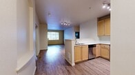 This contemporary 990 square foot apartment in Mill Creek, WA offers a well-designed living space with two bedrooms and two bathrooms. The open-concept layout seamlessly integrates the kitchen, living, and dining areas, creating a spacious feel. The kitchen features light wood cabinetry, stainless steel appliances, and a practical breakfast bar.

The living room is anchored by a modern fireplace with built-in shelving, adding both warmth and character to the space. Large windows throughout provide ample natural light, enhancing the airy atmosphere. Both bedrooms are generously sized, with the primary bedroom measuring 170 square feet.

The bathrooms are well-appointed with wooden vanities, large mirrors, and modern fixtures. The apartment includes an in-unit laundry room with full-sized washer and dryer, adding convenience to daily life. Ample closet space is available throughout, including walk-in closets in the bedrooms.

Durable wood-look flooring runs throughout the apartment, unifying the space and providing easy maintenance. The neutral color palette allows for versatile decorating options. This thoughtfully designed apartment combines functionality with modern aesthetics, offering a comfortable and stylish living environment.