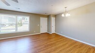 Located at 2582 Friendship Trail in Clinton, Iowa, this well-appointed one-bedroom, one-bathroom unit offers a thoughtfully designed single-level floor plan. The open-concept kitchen and living area serves as the heart of the home, showcasing warm honey-toned hardwood-style flooring throughout. The kitchen is a standout feature, equipped with rich wood cabinetry, dark granite countertops, a mosaic tile backsplash, a center island with additional granite workspace, and a full suite of stainless steel appliances including a refrigerator with ice maker, range, microwave, and dishwasher. The adjacent living and dining area is bright and spacious, featuring a chandelier and natural light from a large window with views of the surrounding neighborhood. The generously sized primary bedroom is carpeted for comfort, includes a ceiling fan with light fixture, and connects to a walk-in closet with built-in shelving and hanging rods, plus a second closet for additional storage. The bathroom features stone-tile flooring and a walk-in shower with a clean white surround. Textured ceilings and neutral walls throughout lend the space a cohesive, move-in-ready aesthetic.