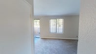 This single-floor residence offers a clean, functional layout designed for comfortable everyday living. The open living and dining area is finished with plush wall-to-wall carpeting, crown molding, and large vertical-blind windows that invite an abundance of natural light and offer views of surrounding greenery. A sliding glass door leads to an outdoor patio area, seamlessly connecting interior and exterior spaces. A ceiling fan enhances the airy feel of the main living space.

The kitchen is well-appointed with white cabinetry, granite-style countertops, and a full suite of stainless steel appliances including a refrigerator, electric range, and microwave. Warm wood-look flooring and a skylight-style ceiling fixture add brightness and character to the culinary space.

The bedrooms are carpeted and filled with natural light through large windows overlooking mature trees. Ample closet storage, including sliding-door closets, ensures practical organization. Neutral wall tones throughout create a calm, versatile backdrop.

The bathrooms feature white vanity cabinetry, granite-style countertops, large mirrors, and brushed nickel fixtures. A full tub-shower combination with a curved curtain rod completes the well-designed bath. The overall ambiance is bright, tidy, and move-in ready.