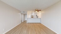 Located at 4240 Harbor Blvd in Oxnard, CA, this 2-bedroom, 2-bathroom residence offers a thoughtfully designed single-floor layout with a bright, clean aesthetic throughout. Light wood-style flooring runs continuously across the living spaces, complementing the neutral white walls and textured ceilings for a cohesive, modern feel.

The open-concept living and kitchen area forms the heart of the home. The kitchen features a peninsula counter with bar seating, white shaker-style cabinetry, stainless steel appliances including a refrigerator, microwave, and range, and a ceiling-mounted light fixture. A ceiling fan anchors the adjoining living area, which flows seamlessly to a private balcony with sliding glass doors that bring in natural light.

The primary bedroom is generously proportioned, offering ample space and access to a dedicated closet with mirrored sliding doors and built-in hanging storage. The second bedroom is equally well-sized with its own closet access. Both bathrooms are finished in a clean, minimal style — one features a wide vanity with white cabinetry, a framed mirror, and light wood flooring, while the second includes a bathtub and shower combination. A dedicated closet provides additional storage for the household.