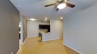 This single-floor space offers an open-concept layout that seamlessly connects the living area to the kitchen, creating a spacious and functional environment. Light hardwood flooring spans the entire space, lending warmth and continuity throughout. The living area is well-lit with recessed lighting and features a ceiling fan with an integrated light fixture, ensuring both comfort and brightness year-round.

The kitchen is a standout feature, outfitted with dark espresso cabinetry that provides a striking contrast against the light walls and flooring. A mosaic tile backsplash adds texture and visual interest, complementing the contemporary aesthetic. The kitchen peninsula, complete with a sink, serves as both a practical workspace and a natural divider between the kitchen and the open living area, offering additional counter space and casual seating potential.

Smooth, light gray walls throughout the space contribute to a clean, modern ambiance, while recessed lighting and a neutral color palette keep the environment feeling airy and open. The thoughtful design maximizes the sense of space, making it highly versatile for a variety of uses. Overall, the space presents a polished, move-in-ready interior with a cohesive modern design language.