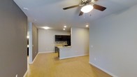 This single-floor space offers an open-concept layout that seamlessly connects the living area to the kitchen, creating a spacious and functional environment. Light hardwood flooring spans the entire space, lending warmth and continuity throughout. The living area is well-lit with recessed lighting and features a ceiling fan with an integrated light fixture, ensuring both comfort and brightness year-round.

The kitchen is a standout feature, outfitted with dark espresso cabinetry that provides a striking contrast against the light walls and flooring. A mosaic tile backsplash adds texture and visual interest, complementing the contemporary aesthetic. The kitchen peninsula, complete with a sink, serves as both a practical workspace and a natural divider between the kitchen and the open living area, offering additional counter space and casual seating potential.

Smooth, light gray walls throughout the space contribute to a clean, modern ambiance, while recessed lighting and a neutral color palette keep the environment feeling airy and open. The thoughtful design maximizes the sense of space, making it highly versatile for a variety of uses. Overall, the space presents a polished, move-in-ready interior with a cohesive modern design language.