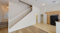 This well-appointed two-story unit offers 3 bedrooms and 2.5 bathrooms, thoughtfully designed for comfortable living. The main level greets you with a dramatic, soaring entryway highlighted by a white-railed staircase and a mix of wood-look vinyl and tile flooring. A half bathroom is conveniently located on the first floor. The kitchen is equipped with light wood cabinetry, granite-style countertops, black appliances including a gas range, built-in microwave, refrigerator, and dishwasher, along with a window that brings in natural light. Sliding glass doors in the dining area open to an outdoor space, enhancing the connection between indoor and outdoor living. Upstairs, the primary suite includes a generously sized walk-in closet and an en suite bathroom featuring dual sinks with granite countertops, a soaking tub, and a separate walk-in shower, all finished with wood-look vinyl flooring. The additional bedrooms are carpeted and receive ample natural light through large windows with views of the surrounding area. A full bathroom with granite countertops and light wood cabinetry serves the secondary bedrooms. Throughout, the neutral color palette and clean finishes create a bright, functional living environment.
