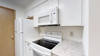 Located at 1600 Belvoir Boulevard in Columbus, Ohio, this single-floor residence offers a well-appointed living space designed with functionality and comfort in mind. The kitchen stands out as a highlight of the home, showcasing crisp white shaker-style cabinetry that extends to the ceiling, maximizing storage capacity throughout. Light granite-patterned countertops provide ample workspace and lend a clean, polished aesthetic to the room. The kitchen is fully equipped with white appliances, including an electric range with a smooth cooktop, an over-the-range microwave with built-in ventilation, and a full-size refrigerator, creating a cohesive and practical cooking environment. The bright, neutral color palette throughout the kitchen contributes to an open and airy feel. The single-level layout of the home ensures easy accessibility and a seamless flow between living areas. The overall design emphasizes clean lines and a timeless aesthetic, making the space both inviting and practical for everyday living. This residence at Belvoir Boulevard presents a well-maintained interior that balances modern convenience with understated style.