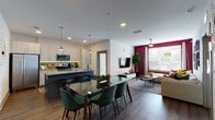 Located at 1040 Jamison Loop in Kissimmee, Florida, this single-floor residence offers a thoughtfully designed open-concept layout that seamlessly connects the kitchen, dining, and living areas. The modern kitchen is outfitted with light wood cabinetry, granite countertops, stainless steel appliances, and a central island with bar seating — ideal for both everyday cooking and entertaining. Pendant lighting and under-cabinet illumination add warmth and functionality to the space. The dining area accommodates a full-sized table, flowing naturally into the living room, which features rich hardwood-style flooring, a bold crimson accent wall, large windows that invite natural light, and a ceiling fan overhead. A dedicated home office provides carpeted flooring, a generous work surface, and ample natural light through wide windows — perfect for remote work or study. The primary bedroom showcases a striking teal accent wall, plush carpeting, and large windows. The en-suite bathroom includes granite vanity countertops, a glass-enclosed walk-in shower, and a sliding barn door. A second full bathroom offers a soaking tub with shower combo and matching granite finishes. Throughout the residence, consistent modern design elements and vibrant color accents create a cohesive, contemporary living environment.