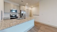 Located at 2201 TX-195 in Georgetown, TX, this two-story, one-bedroom, one-bathroom residence offers a thoughtfully designed layout across two levels. The main living level features an open-concept kitchen equipped with stainless steel appliances — including a French door refrigerator, electric range, and built-in microwave — complemented by granite countertops, a peninsula island with an undermount sink, and soft-toned shaker-style cabinetry. Light wood-look flooring runs consistently throughout, contributing to a clean, cohesive aesthetic. Recessed lighting and crisp white walls keep the space feeling bright and airy. The bathroom is outfitted with a full tub-shower combo with white tile surround, a granite-topped vanity, and matching sage-toned cabinetry. The bedroom is a cozy, well-proportioned retreat featuring a large window that invites natural light and outdoor views. A dedicated walk-in closet with full-width shelving and a hanging rod provides ample storage. Five-panel interior doors and clean baseboards add a polished, modern touch throughout. The second level includes a private balcony, offering outdoor space for relaxation. A staircase connects the two floors, completing this efficiently designed and move-in-ready residence.