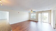 Located at 870 Plantation Rd in Blacksburg, VA, this well-appointed one-bedroom, two-bathroom residence offers a thoughtfully designed single-floor layout. Rich hardwood-style flooring flows throughout the main living areas, creating a warm and cohesive aesthetic. The open-concept living, dining, and kitchen area forms the heart of the home, filled with natural light from large windows and a sliding glass door that leads to a private patio. A ceiling fan overhead enhances comfort in the spacious living area. The kitchen is equipped with warm wood cabinetry, dark countertops, black appliances including a full-size refrigerator and range, and a generous peninsula breakfast bar that seamlessly connects the kitchen to the dining and living space. Track lighting adds a functional, modern touch. The bedroom features plush carpeting, a ceiling fan, a bright window, and a well-sized closet with built-in shelving. The unit includes two full bathrooms: one with a tub-shower combination and wood-toned vanity, and a second featuring a stand-alone glass-door shower, both finished with hardwood-style flooring. Ample storage is provided through five closets and a pantry, complemented by a hallway that connects the private and common areas of the home.