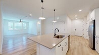 Located at 3200 Medical Center Drive in McKinney, TX, this well-appointed 2-bedroom, 2-bathroom residence offers a thoughtfully designed single-floor layout with a clean, modern aesthetic. Light-toned luxury vinyl plank flooring runs consistently throughout, unifying the space and enhancing its bright, airy feel.

The open-concept kitchen and living area serves as the heart of the home. The kitchen is outfitted with white shaker-style cabinetry, quartz countertops, a white subway tile backsplash, and stainless steel appliances including a range, over-the-range microwave, and French door refrigerator. A central island with an undermount sink, matte black fixtures, and stylish pendant lighting provides additional prep and dining space, while recessed lighting ensures the area is well-lit throughout.

The living room is open and generously proportioned, with natural light filtering in through large windows. Both bedrooms continue the clean, neutral palette, featuring ceiling fans, windows with blinds, and ample closet access. The primary bedroom offers a comfortable footprint with access to a full bathroom featuring a dual-sink vanity with quartz countertops, white cabinetry, and a dedicated walk-in closet. A hallway connects the space's three closets and two full bathrooms efficiently. The overall ambiance is modern, clean, and move-in ready.