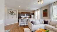 This well-appointed 3-bedroom, 2-bathroom single-floor residence at 9641 N Ambassador Dr in Kansas City, MO offers a thoughtfully designed open-concept layout. The combined living, dining, and kitchen area forms the heart of the home, featuring warm wood-look flooring, recessed lighting, and an abundance of natural light from multiple large windows dressed with sheer curtains. The kitchen is outfitted with dark espresso cabinetry, granite countertops, stainless steel appliances, and a central island with bar seating — ideal for both cooking and entertaining. The adjacent dining area accommodates a full-sized table, while the living room provides a comfortable, airy retreat with a ceiling fan overhead. The spacious primary bedroom features plush carpeting, a ceiling fan, and a large window with outdoor views. The primary bathroom impresses with a dual-sink vanity, granite countertops, dark wood cabinetry, and elegant wall-mounted lighting. Both closets offer built-in shelving and hanging storage. A dedicated laundry area houses a full-size washer and dryer with overhead shelving. The neutral, modern color palette and cohesive finishes throughout lend the space a clean, inviting ambiance.