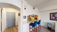 Located at 515 W Franklin St in Richmond, VA, this one-bedroom, one-bathroom unit offers a thoughtfully organized single-floor layout that makes excellent use of its compact footprint. The living area features hardwood-style flooring and flows seamlessly toward the kitchen, which is connected via a distinctive arched pass-through bar with a built-in sink — an architectural detail that adds both character and functionality. The kitchen itself is equipped with warm wood cabinetry, tile flooring, a full-size refrigerator, and an electric range, providing all the essentials for everyday cooking. Elegant arched doorways and crown molding carry through the common areas, lending a classic, refined aesthetic to the space. The bedroom is carpeted for comfort and features a ceiling fan and a window that invites natural light, creating a cozy and restful retreat. The full bathroom includes a tiled tub-surround shower, tile flooring, and wood-toned cabinetry offering ample storage. A dedicated laundry area adds practical convenience. A hallway with closet storage connects the rooms efficiently. The unit's clean white walls and consistent finishes throughout create a bright, cohesive ambiance well-suited for comfortable urban living in the heart of Richmond.