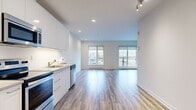 Located at 8035 Boulevard Saint-Laurent in Brossard, QC, this well-appointed one-bedroom, one-bathroom unit offers a thoughtfully designed open-concept layout finished with light hardwood-style flooring throughout. The combined kitchen and living area forms the heart of the unit, where a sleek, modern kitchen stands out with white high-gloss cabinetry, a white tile backsplash, and a full suite of stainless steel appliances including a fridge, electric range, over-the-range microwave, and dishwasher. A gold-toned faucet adds a refined touch to the undermount sink. The living area is bright and airy, benefiting from large windows that frame outdoor views and flood the space with natural light. A wall-mounted split air conditioning unit ensures year-round comfort. The bedroom is a comfortable, quiet retreat featuring a window with outdoor views and generous floor space. A dedicated closet provides convenient storage. The bathroom is cleanly finished with large-format white wall tiles, a soaker tub with a glass panel and adjustable shower, and warm wood-toned cabinetry paired with a clean white vanity. Recessed and track lighting throughout the unit enhance its modern, minimalist aesthetic.