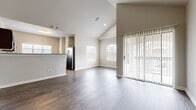 This single-story, 2-bedroom, 2-bathroom home offers a thoughtfully designed layout with quality finishes throughout. The open living area immediately impresses with soaring vaulted ceilings, dark hardwood-style flooring, and an abundance of natural light streaming through multiple windows and a sliding glass door with vertical blinds that opens to the exterior. An arched window adds an elegant architectural touch to the bright living space.

The kitchen is well-equipped with rich dark cabinetry, granite countertops, a classic subway tile backsplash, and a full suite of stainless steel appliances including a range, microwave, and dishwasher. A large window over the sink brings in generous natural light.

Both bathrooms continue the home's refined aesthetic with granite-topped dark wood vanities and wood-style tile flooring. The primary bath features a private water closet, while the secondary bath includes a tiled shower-tub combination.

The two bedrooms are carpeted for comfort and offer a calm, neutral palette. The spacious primary bedroom features elevated ceilings and access to a walk-in closet with built-in shelving and hanging rods. The secondary bedroom is bright and airy, with a window overlooking the exterior. Hallways connect the rooms efficiently, completing this well-organized and move-in-ready home.