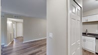 This single-floor, two-bedroom, one-and-a-half-bathroom unit in Inkster, Michigan, offers a well-designed layout with a cohesive, neutral color palette throughout. Wood-look plank flooring runs through the main living areas, creating a clean and contemporary aesthetic that ties the spaces together.

The living room is a spacious, light-filled area highlighted by a sliding glass door that opens to a private balcony overlooking mature trees, allowing natural light to flow freely into the room. The adjoining hallway connects seamlessly to the rest of the unit.

The kitchen is efficiently arranged with ample white shaker-style cabinetry, gray countertops, a stainless steel sink, and a full suite of stainless steel appliances, including an electric range, refrigerator, and dishwasher. A built-in range hood completes the functional workspace.

Both bedrooms feature plush carpeting and closet storage. The primary bedroom includes an en-suite bathroom, while the second bedroom offers a window with natural light and a reach-in closet. The full bathroom includes a tub-shower combination with clean white tile surround, brushed nickel fixtures, and wood-look flooring, maintaining the consistent modern finish found throughout the unit.