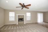 This two-floor home offers a functional and well-organized layout across both levels. The main floor centers around a generously sized living area with plush carpeting, a ceiling fan, and decorative columns that add architectural interest. A stone-accented fireplace anchors one end of the room, while sliding glass doors flood the space with natural light and provide access to an outdoor patio. The kitchen features warm honey-toned oak cabinetry, granite-look countertops, tile flooring, and black appliances including a range, built-in microwave, and dishwasher, all arranged for efficient use of space.

Upstairs, the primary bedroom stands out with soaring vaulted ceilings, a ceiling fan, and soft carpeting. It connects directly to a spacious en-suite bathroom equipped with dual vanities, a large soaking tub, tile flooring, and a private water closet. A generous walk-in closet with wire shelving provides ample storage. An additional full bathroom on the upper level includes a single vanity, tub-shower combo, and tile flooring. A wood-railed staircase with a decorative transom window connects the two floors, contributing to the home's traditional character. Neutral gray and beige tones are carried throughout, creating a cohesive and move-in-ready atmosphere.