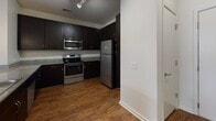 Located in Mount Pleasant, South Carolina, this single-floor residence offers a well-organized layout designed for comfortable everyday living. The open living and dining area is finished with rich, dark wood-style hard flooring that extends throughout the main living spaces, complemented by neutral white walls and ceiling fans that provide both light and air circulation. Natural light enters through windows fitted with horizontal blinds, creating a bright and welcoming atmosphere.

The kitchen is outfitted with dark espresso-toned cabinetry, granite countertops, and a full suite of stainless steel appliances, including a range, over-the-range microwave, and refrigerator. Track lighting overhead enhances visibility and adds a contemporary touch. A raised breakfast bar provides an informal dining or workspace option adjacent to the kitchen.

The bedrooms feature plush wall-to-wall carpeting and ceiling fans, each with windows that allow natural light to filter in. Multiple bedrooms provide flexible use of space. An electrical panel is conveniently accessible within one of the rooms.

The bathrooms are finished with light tile flooring, dark vanity cabinetry with granite countertops, and full tub-shower combinations with brushed nickel fixtures, maintaining a clean and consistent aesthetic throughout the unit.