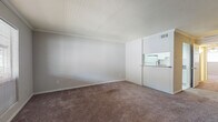This single-floor, one-bedroom, one-bathroom unit is thoughtfully designed to maximize comfort and functionality. The living area is spacious and open, featuring wall-to-wall carpeting in warm neutral tones, crisp white walls with crown molding, and a seamless connection to the kitchen via a pass-through counter — ideal for everyday living and entertaining. The kitchen is equipped with granite-style countertops, white cabinetry, a coil-burner range with overhead ventilation, and ample storage, offering a practical and clean workspace. The bedroom provides a generous footprint, also finished with plush carpeting, and includes a mirrored sliding-door closet with built-in shelving and hanging rods, offering well-organized storage solutions. The bathroom is a standout feature, finished with large-format marble-look porcelain tile on both the floors and walls, a soaking tub with a tiled surround, a white vanity with granite countertop and brushed nickel hardware, and a toilet — all contributing to a polished, spa-like atmosphere. Throughout the unit, a consistent neutral color palette and clean finishes create a cohesive and inviting ambiance.