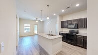 Located at 255 Fairview Rd in Henrietta, TX, this single-floor residence offers a thoughtfully designed 2-bedroom, 2-bathroom layout with a cohesive blend of modern finishes throughout. The open-concept kitchen and living area forms the heart of the home, anchored by a granite-topped island with an integrated sink and elegant pendant lighting overhead. Dark espresso cabinetry contrasts beautifully with the light granite countertops, while black appliances — including a range, microwave, and refrigerator — complete the kitchen. Light wood-look flooring runs through the main living areas, contributing to a bright, airy atmosphere. The living room features a ceiling fan, recessed lighting, and a glass-panel entry door that invites natural light. Both bedrooms are carpeted and equipped with ceiling fans and windows. The primary bedroom includes access to a private bathroom with a granite-top vanity, dark cabinetry, and a tub-shower combination. The second bathroom mirrors this design with similar finishes. Three closets provide ample storage throughout the unit. The layout flows efficiently through two hallways, connecting all areas seamlessly for comfortable everyday living.