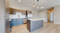 Located at 4328 Provision Pky in Fort Wayne, Indiana, this single-floor unit offers a thoughtfully designed, modern living space finished with light wood-look flooring and neutral tones throughout. The contemporary kitchen serves as a central highlight, featuring two-tone cabinetry — warm wood uppers paired with cool-toned lower cabinets — a decorative herringbone tile backsplash, stainless steel appliances including a French door refrigerator and dishwasher, a matte black faucet, and a large center island with a crisp white quartz countertop illuminated by stylish pendant lighting. The open living area is bright and airy, benefiting from natural light streaming through large windows and a sliding glass door that opens to a private balcony with neighborhood views. Bedrooms are generously proportioned with ample natural light, panel-style white doors with matte black hardware, and access to spacious walk-in closets outfitted with wire shelving systems. The bathroom is cleanly appointed with a wood-toned vanity, white quartz countertop, rectangular mirror, and a shower-tub combo with matte black fixtures. A dedicated laundry room accommodates a full-size washer and dryer with overhead wire shelving for additional storage. Recessed lighting and consistent finishes create a cohesive, move-in-ready aesthetic throughout the entire space.