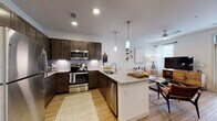 This 1-bedroom, 1-bathroom residence is thoughtfully designed with a contemporary open-concept layout that seamlessly connects the kitchen, dining, and living areas. The kitchen is a standout feature, showcasing rich dark cabinetry, a classic subway tile backsplash, granite countertops, a full suite of stainless steel appliances, and a peninsula island with pendant lighting — ideal for both meal prep and casual entertaining. Light wood-style flooring flows through the main living areas, enhancing the bright and airy atmosphere created by large windows and recessed lighting. The living room offers generous space, a ceiling fan, and access to an outdoor area through a glass door framed by abundant natural light. A dedicated dining nook provides a comfortable setting for seated meals. The bedroom is a calm retreat with plush carpeting, soft neutral tones, and a sizable window that fills the room with natural light. The bathroom features a clean, minimalist design with a tub-shower combination and consistent wood-style flooring. A laundry area is also included within the unit, adding everyday convenience to this well-rounded single-floor residence.
