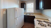 Located at 4310 Chamberlayne Ave in Richmond, Virginia, this single-floor unit presents a straightforward and functional layout with several consistent design elements carried throughout. Rich hardwood floors flow continuously across the living areas and multiple rooms, lending warmth and character to the space. The walls are finished in a soft gray tone, complemented by crisp white trim and baseboards that frame each room cleanly.

Multiple rooms feature cast-iron radiators positioned beneath double-hung windows, providing both heating and an architectural nod to the building's older construction. The windows allow natural light to enter generously, with views of the surrounding neighborhood visible from several rooms. A classic six-panel white entry door with brass hardware serves as the main entrance into the open living area.

The kitchen is equipped with dark cabinetry, a double stainless steel sink, a gas range, and a full-size refrigerator. A window above the sink brings in additional natural light. The bathroom includes a full soaking tub with a tiled surround in white, accented by a window that adds ventilation and light to the space.

The floor plan, as seen in the dollhouse view, reveals a compact but well-divided layout with multiple rooms branching from a central corridor, offering practical separation of living spaces throughout.