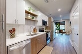 Located at 4646 Dodge St in Omaha, Nebraska, this one-bedroom, one-bathroom unit offers a thoughtfully designed layout across a single floor. The interior showcases a modern aesthetic, with wood-look plank flooring running throughout and a clean, neutral color palette that creates a bright and cohesive atmosphere.

The galley-style kitchen is a standout feature, equipped with stainless steel appliances including a dishwasher, range, microwave, and refrigerator. Warm wood cabinetry on the lower half is complemented by crisp white upper cabinets and open floating shelves, all set against a classic white tile backsplash. White quartz countertops and recessed lighting add a polished, contemporary finish. The kitchen flows directly into the combined dining and living area, which benefits from a large floor-to-ceiling window that invites natural light and outdoor views.

The generously sized bedroom features oversized windows with views of the surrounding neighborhood, providing ample natural light. A dedicated walk-in closet offers substantial hanging and storage space with built-in shelving rods.

The bathroom is well-appointed with a wood-toned vanity, white countertop, a full tub-shower combination, and wood-look tile flooring, maintaining the design consistency found throughout the unit. The entryway includes a bold navy door that adds a striking design accent upon arrival.