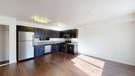 Located at 2500 Lancaster Dr in Richmond, CA, this single-floor unit offers a well-designed, functional layout with a cohesive aesthetic throughout. The kitchen is a standout feature, showcasing rich dark espresso cabinetry with sleek hardware, granite countertops, and a full suite of stainless steel appliances including a refrigerator, gas range, microwave, and dishwasher. Flush-mount ceiling fixtures illuminate the space, which flows seamlessly into the open living area. The living and main areas feature warm hardwood-style flooring that runs throughout much of the unit, reflecting natural light that pours in through large windows dressed with vertical blinds. The living area is generously proportioned, offering an open and airy feel with clean white walls and a bright, welcoming ambiance. The bedroom is carpeted for comfort and also benefits from natural light via a large window. Closet storage is conveniently accessible. The bathroom is well-appointed with a dark vanity topped with a granite countertop, a mirrored medicine cabinet, overhead vanity lighting, and a full tub and shower combination. Accessibility-friendly grab bars are also present. Throughout the unit, the design maintains a clean, modern character with a consistent use of dark cabinetry contrasted against bright white walls and ceilings.