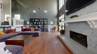 Located at 3925 Satellite Blvd in Duluth, Georgia, this single-floor community space offers a thoughtfully designed layout that balances comfort, functionality, and modern style across a generously sized floor plan. The living room serves as the centerpiece of the space, boasting soaring ceilings, rich hardwood flooring, and a dramatic floor-to-ceiling stone fireplace with a white decorative mantel. Large windows and glass doors flood the room with natural light, while open shelving and comfortable seating create a welcoming, communal atmosphere. Adjacent to the living area, the dining room features light wood-look flooring, recessed lighting, and multiple round white tables paired with sleek black chairs, with French doors opening to outdoor views. The kitchen is well-appointed with dark cabinetry, a bold geometric tile backsplash, granite countertops, a peninsula with bar seating, and full appliances, making it ideal for gathering and entertaining. A dedicated co-working lounge rounds out the space, offering a long wall-mounted desk with computer workstations, stylish pendant lighting, patterned wallpaper, and a high-top communal table — all designed to support productivity in a modern, inviting environment.