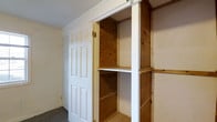 This single-floor storage room is designed with functionality at its core, offering a dedicated space for organized storage needs. The room features a built-in shelving unit constructed from natural wood, with multiple tiers providing ample space for storing a variety of items. The shelving is framed with exposed wooden studs, giving it a sturdy, utilitarian character. A classic six-panel white door provides clean, traditional access to the space, complementing the room's neutral color palette. The walls are finished in a light tone, contributing to a bright and open feel despite the room's practical nature. The concrete floor adds to the durable, no-frills aesthetic suited for a storage environment. The ceiling is smooth and unadorned, keeping the focus on the room's storage functionality. Overall, this storage room strikes a balance between practicality and basic craftsmanship, making it a versatile solution for organizational needs.