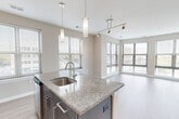 Unit 318 at 3400 Columbia Pike in Arlington, VA is a well-appointed 2-bedroom, 2-bathroom residence offering a thoughtfully designed single-floor layout. The open-concept living, dining, and kitchen area serves as the heart of the home, featuring light wood-style flooring and an abundance of natural light streaming through multiple large windows fitted with horizontal blinds that frame urban views of the surrounding Arlington streetscape.

The kitchen is a standout, centered around a granite-topped island with an undermount sink and pendant lighting overhead. Dark espresso cabinetry provides generous storage, complemented by a subway-tile backsplash and a full suite of stainless steel appliances including a refrigerator, range, microwave, and dishwasher. Track lighting runs across the ceiling, adding a modern, functional touch.

Both bedrooms feature plush carpeting and neutral wall tones, creating a calm and comfortable atmosphere. The primary bedroom is generously sized, while the second bedroom benefits from its own large window with outdoor views. Three closets are distributed throughout the unit for ample storage. An in-unit laundry area adds everyday convenience.

The bathrooms are finished with large-format tile flooring, dark vanity cabinetry, granite countertops, and a tiled tub-shower combination with a decorative accent tile border. The overall design is clean, contemporary, and functional.