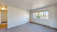 Located at 1431–1435 NE Merman Dr in Pullman, Washington, this single-floor, 3-bedroom, 2-bathroom unit offers a practical and functional layout. The kitchen features warm-toned wood cabinetry, white appliances including an electric range and refrigerator, light hard-surface flooring, and direct access to an outdoor balcony that brings in abundant natural light. Adjacent to the kitchen is a dedicated dining area with a ceiling light fixture and matching hard-surface flooring.

The three bedrooms are carpeted and each includes a baseboard heater and a window overlooking the surrounding landscape of mature trees and greenery. The primary bedroom is the most spacious of the three, offering a comfortable footprint for furnishing. Two closets provide dedicated storage throughout the unit.

Both bathrooms are similarly appointed, each featuring a tub-shower combination with tile surround, a wood-vanity with countertop sink, a mirror, and light speckled flooring. One closet shares space with a water heater, offering additional utility storage. Baseboard heating is present throughout the unit, and textured ceilings are featured in select rooms.