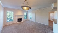 This single-floor residence offers a thoughtfully designed layout that balances comfort and functionality throughout. The living room serves as the heart of the home, featuring plush wall-to-wall carpeting, crown molding, a ceiling fan with a decorative light fixture, and a tile-surround fireplace flanked by windows that allow natural light to fill the space. A dedicated entry door leads directly into this welcoming area.

The kitchen is efficiently arranged in a galley-style configuration, outfitted with warm honey-toned wood cabinetry, laminate countertops, a double stainless steel sink, and white appliances including a refrigerator, electric range, and built-in microwave. Dark hardwood-style flooring adds contrast to the bright cabinetry. A pass-through counter opens to the adjacent dining or living area, enhancing the open feel of the space.

The bedroom is generously sized, finished with soft carpeting, a ceiling fan, and a large window fitted with blinds that bring in abundant natural light. The bathroom is clean and practical, featuring a vanity with storage, a wall-mounted wood cabinet, and a tiled shower. A dedicated in-unit laundry room provides added convenience, housing a full-size washer and dryer. The overall ambiance is neutral, clean, and move-in ready.