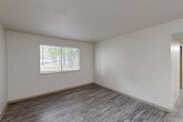 Located at 515 George Wallace Dr in Gadsden, Alabama, this single-story, 3-bedroom, 2-bathroom home offers a practical and well-organized layout. The interior features a mix of durable hardwood-style vinyl flooring in the main living areas and soft carpeting in the bedrooms, providing comfort and easy maintenance throughout.

The living area greets you with a bright, open feel, highlighted by a front entry door flanked by vertical blinds and a flush-mounted ceiling light. Neutral white walls and textured ceilings run consistently throughout the home, creating a clean, cohesive aesthetic.

The kitchen is equipped with warm oak-toned cabinetry, ample upper and lower storage, a black electric range with overhead ventilation, a black refrigerator, and a stainless steel sink — all set atop light hardwood-style flooring.

The spacious primary bedroom offers a generous footprint, with a large window framing views of mature surrounding trees and abundant natural light. Each bedroom includes closet storage, with five closets total distributed across the home. Two hallways provide smooth connectivity between rooms.

Both bathrooms feature hardwood-style flooring, vanities with under-sink cabinetry, and mirrors with overhead lighting. One bathroom includes a full tub/shower combo. The home's efficient, single-floor design makes it highly accessible and easy to navigate.