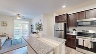 This thoughtfully designed one-bedroom, one-bathroom unit offers an efficient and cohesive layout with consistent finishes throughout. Light hardwood-style flooring flows through every room, complementing the neutral white walls and creating a bright, clean aesthetic.

The open-concept kitchen and living area serves as the heart of the unit. The kitchen is well-appointed with rich dark wood cabinetry, granite countertops, a full suite of stainless steel appliances including a refrigerator, range, microwave, and dishwasher, and a central island that provides additional prep and dining space. Recessed lighting adds a polished touch overhead.

The living room is comfortably sized, featuring a ceiling fan, and is brightened by large sliding glass doors that open to an outdoor area, allowing natural light to fill the space throughout the day.

The bedroom is a generously proportioned retreat with a ceiling fan, a window offering natural light and outdoor views, and ample floor space. A hallway connects the bedroom to the full bathroom, which mirrors the kitchen's aesthetic with dark wood cabinetry, granite countertops, and a large vanity mirror.