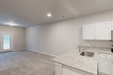 This contemporary single-story residence at 2308 Holiday Loop, Reidsville, NC offers 1060 square feet of thoughtfully designed living space. The home features three bedrooms, including a generous 190 square foot primary suite, and two full bathrooms. The interior showcases a harmonious blend of materials, with plush carpeting in the bedrooms and durable wood-look flooring in common areas.

The heart of the home is a modern, open-concept kitchen equipped with stainless steel appliances, ample white cabinetry, and sleek granite countertops. A convenient breakfast bar provides additional seating and seamlessly connects the kitchen to the living area.

Large windows throughout allow for abundant natural light, creating a bright and airy atmosphere. The bathrooms feature clean lines with white fixtures and wood-look flooring, while the primary bath boasts a dual-sink vanity for added convenience.

Additional amenities include a dedicated laundry room, built-in closet systems, and a ceiling fan in the living area for improved air circulation. French doors in the main living space lead to an outdoor area, perfect for extending the living space during pleasant weather.

The neutral color palette and contemporary finishes provide a blank canvas for various design styles, making this home an ideal choice for those seeking a move-in ready property with modern comforts.