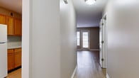 Located at 1100 Deer Path in Lakewood, NJ, this single-floor, 2-bedroom, 1-bathroom home offers a practical and comfortable layout across a generously sized floor plan. Light-toned hardwood-style flooring runs throughout the living spaces, lending a clean, cohesive look to the interior.

The entry hallway connects seamlessly to the main living areas, with natural light filtering in through a glass-paneled front door. The open dining and living area is spacious and bright, featuring neutral taupe walls, large windows with outdoor views of the surrounding neighborhood, and a glass door that enhances the sense of openness.

The kitchen is conveniently accessible via a pass-through window from the dining area, outfitted with warm honey-toned wood cabinetry, light stone-finish countertops, and a gas range with overhead ventilation.

The primary bedroom is generously proportioned, featuring a large window that fills the room with natural light. The second bedroom also benefits from a bright window and includes a built-in closet with sliding panel doors, providing ample storage.

The full bathroom is clean and functional, offering a full soaking tub with shower, a toilet, and light wood-style flooring that mirrors the rest of the home. A dedicated closet rounds out the storage options within this well-organized and move-in-ready residence.