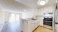 Located at 6929 Kester Ave in Van Nuys, Los Angeles, this single-story one-bedroom unit offers a thoughtfully arranged floor plan that maximizes its compact footprint. The open-concept kitchen and living area form the heart of the space, with the kitchen anchored by a peninsula that provides additional counter space and doubles as a casual dining surface. White cabinetry with brushed nickel hardware lines the walls, complemented by stainless steel appliances including a gas range, dishwasher, and refrigerator. Tile flooring runs through the kitchen, while light wood-look laminate flooring extends throughout the living area and bedroom, adding warmth and visual continuity. The living room benefits from a sliding glass door that opens to an outdoor balcony, allowing natural light to fill the room. A distinctive vertical board-and-batten accent wall adds a modern design touch to the living space. The generously sized bedroom features mirrored sliding closet doors and its own board-and-batten wall paneling, creating a cohesive aesthetic. A hallway connects the main living areas to the bedroom, completing the efficient layout. Textured ceilings and flush-mount lighting fixtures are consistent throughout the unit.