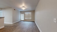 This single-floor unit offers a practical and efficiently designed layout, accommodating five bedrooms and two bathrooms within a compact footprint. Wood-look flooring runs consistently throughout the space, complementing the neutral, light gray and beige wall tones that create a clean, cohesive aesthetic.

The living area features a door with adjacent windows dressed in horizontal blinds, allowing natural light to filter in while maintaining privacy. A flush-mount light fixture provides additional illumination. Several bedrooms echo this design, each featuring wood-look flooring, neutral walls, and windows with blinds that bring in natural light.

The kitchen is equipped with warm-toned wooden cabinetry, granite-style countertops, and black appliances including a gas range, refrigerator, dishwasher, and microwave. Light wood-look flooring continues here, maintaining visual consistency.

The bathrooms include accessibility-oriented features such as grab bars around the tub-shower combo and an open-clearance vanity with a single sink and large mirror. A dedicated closet includes wire shelving and hanging rods, providing organized storage. The overall ambiance is functional, clean, and move-in ready.