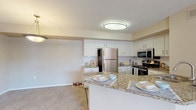 Located at 5700 22nd St N in Saint Petersburg, Florida, this two-story home offers a well-designed layout with functional living spaces spread across both levels. The kitchen serves as a central highlight, equipped with stainless steel appliances including a refrigerator, range, and built-in microwave. White shaker-style cabinetry pairs with granite countertops and a subway tile backsplash, while a peninsula provides additional prep and dining space. Light wood-style flooring runs throughout the kitchen, complementing the neutral, warm tones found throughout the home.

The bedrooms are carpeted and filled with natural light through large windows with views of surrounding greenery. Vaulted ceilings in one bedroom add a sense of openness. The bathrooms feature granite-topped vanities with white cabinetry and light wood flooring, maintaining a consistent aesthetic throughout. A dedicated laundry room with overhead cabinetry accommodates a full-sized washer and dryer. The upper level includes a railed landing area with hardwood-style flooring, connecting the various rooms in a practical and cohesive layout. Overall, the home presents a clean, move-in-ready aesthetic with modern finishes.