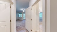 Located at 127 Inspiration Ave in Bluffton, SC, this single-floor residence offers a practical and well-designed layout across two bedrooms and two bathrooms. A central hallway connects the living spaces, providing a logical flow throughout the home.

The kitchen is a standout feature, equipped with stainless steel appliances including a refrigerator, electric range, and microwave. White shaker-style cabinetry extends to the ceiling, offering generous storage, while granite countertops and a peninsula with a double-basin sink add both function and visual appeal. Light wood-look flooring and pendant lighting complete the space.

The living area is carpeted and bright, with multiple windows and a glass door opening to a private balcony, allowing ample natural light and outdoor views. A ceiling fan adds comfort to the space.

Both bedrooms are carpeted and well-lit, each featuring windows with views of surrounding greenery and ceiling fans. The spacious primary bedroom provides a generous footprint. The bathrooms mirror the kitchen's aesthetic, featuring granite countertops, white cabinetry, and clean, neutral finishes throughout.