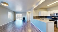Located at 2620 S Miller Dr in Lakewood, CO, this well-appointed one-bedroom, one-bathroom residence offers a thoughtfully designed single-floor layout. The open-concept living and dining area is anchored by rich hardwood-style flooring and a classic corner fireplace with a white surround, creating a warm and inviting atmosphere. Large sliding glass doors lead to a private balcony, flooding the space with natural light and providing outdoor views. The kitchen features crisp white shaker cabinetry, light quartz countertops, a slate-blue subway tile backsplash, and stainless steel appliances including a range, microwave, and refrigerator, complemented by a pantry for added storage. A breakfast bar-style peninsula connects the kitchen to the living area. The spacious bedroom is finished with plush carpet, two generously sized windows, and access to a walk-in closet. The bathroom includes a white vanity with quartz countertop, a tub/shower combination, and hardwood-style flooring. Additional highlights include a dedicated laundry area with a full-size washer and dryer, three closets for ample storage, and a hallway that connects all spaces efficiently. Neutral tones throughout lend a clean, move-in-ready appeal.