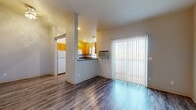 Located at 12423 E Mansfield Ave in Spokane Valley, WA, this single-story, one-bedroom, one-bathroom unit offers a practical and well-organized layout. The combined kitchen and living area serves as the heart of the home, featuring durable hardwood-style flooring throughout. A wall-mounted HVAC unit provides climate control, while a large sliding glass door with vertical blinds fills the living space with natural light. The kitchen is a standout feature, offering abundant warm-toned wooden cabinetry, dark granite-style countertops, a full suite of white appliances including a gas range, dishwasher, refrigerator, and built-in microwave, plus recessed lighting overhead. The spacious bedroom is finished with plush carpeting, a ceiling fan with light fixture, and a window for natural light. It features two generous closets with sliding doors, providing excellent storage. The full bathroom includes hardwood-style flooring, a single-sink vanity with matching cabinetry and dark countertops, a toilet, and a full-size soaking tub with shower. A hallway connects the main living areas seamlessly, completing this efficiently designed and well-appointed unit.