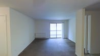This single-floor space presents a clean, open living area designed with simplicity and functionality in mind. The room is finished with wall-to-wall neutral-toned carpet, providing a comfortable and cohesive foundation throughout the space. Bright white walls and a smooth white ceiling contribute to an airy, open atmosphere, maximizing the sense of space within the room.

A key feature of this living area is the sliding glass door that leads directly to a private balcony, allowing natural light to filter into the interior while offering outdoor access and views beyond. The balcony is enclosed with a railing, providing a secure outdoor extension of the living space.

Along one wall, a low-profile baseboard heater provides climate control, keeping the space practical for year-round comfort. The overall layout is open and flexible, offering ample room for a variety of furniture arrangements. The minimalist design of the space, with its neutral palette and uncluttered lines, creates a versatile canvas that can accommodate a range of interior styles and personal preferences.