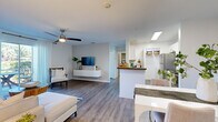 Located at 4132 53rd Ave W in Bradenton, Florida, this single-story residence offers a well-designed, open-concept layout filled with natural light and contemporary finishes throughout. The living area is anchored by wood-look flooring, a ceiling fan, and a sliding glass door that frames outdoor views and floods the space with Florida sunshine. A floating media console and neutral wall tones contribute to the clean, modern aesthetic.

The kitchen is thoughtfully arranged with white shaker cabinetry, dark countertops, stainless steel appliances including a refrigerator, dishwasher, and range, and a pass-through counter that opens toward the dining area. A dedicated pantry closet provides additional storage. An entry hallway features a reach-in closet for added convenience.

The bedrooms are carpeted for comfort, each equipped with ceiling fans and walk-in closets with wire shelving systems. Natural light enters through windows with views of surrounding greenery. The bathroom offers a single-sink vanity with dark countertops, white cabinetry, and a tub-shower combination. A dedicated laundry area houses a full-sized washer and dryer with overhead shelving, rounding out the functional and comfortable design of this Bradenton residence.
