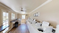 Located at 854 Vine St in Oceanside, this single-story community laundry facility is designed to accommodate high-volume use while maintaining a clean, comfortable environment. The space is thoughtfully laid out, with a row of top-loading washing machines lining one wall and a bank of stacked dryer units positioned along the opposite side, providing generous machine capacity for residents.

The interior features warm, neutral-toned walls complemented by crown molding that adds a refined architectural detail throughout. Hardwood-style flooring runs the length of the facility, offering both durability and visual appeal. A ceiling fan with a light fixture promotes air circulation, while multiple windows allow natural light to fill the space and offer views of the surrounding greenery outdoors.

Dark granite folding counters are positioned along the walls, providing practical surfaces for sorting and folding laundry. A glass-paneled entry door leads directly to the exterior pathway, enhancing accessibility and ventilation. Posted informational signage and conveniently placed waste bins contribute to the facility's organized, user-friendly layout. Overall, the space strikes a balance between functionality and a well-maintained, welcoming atmosphere.